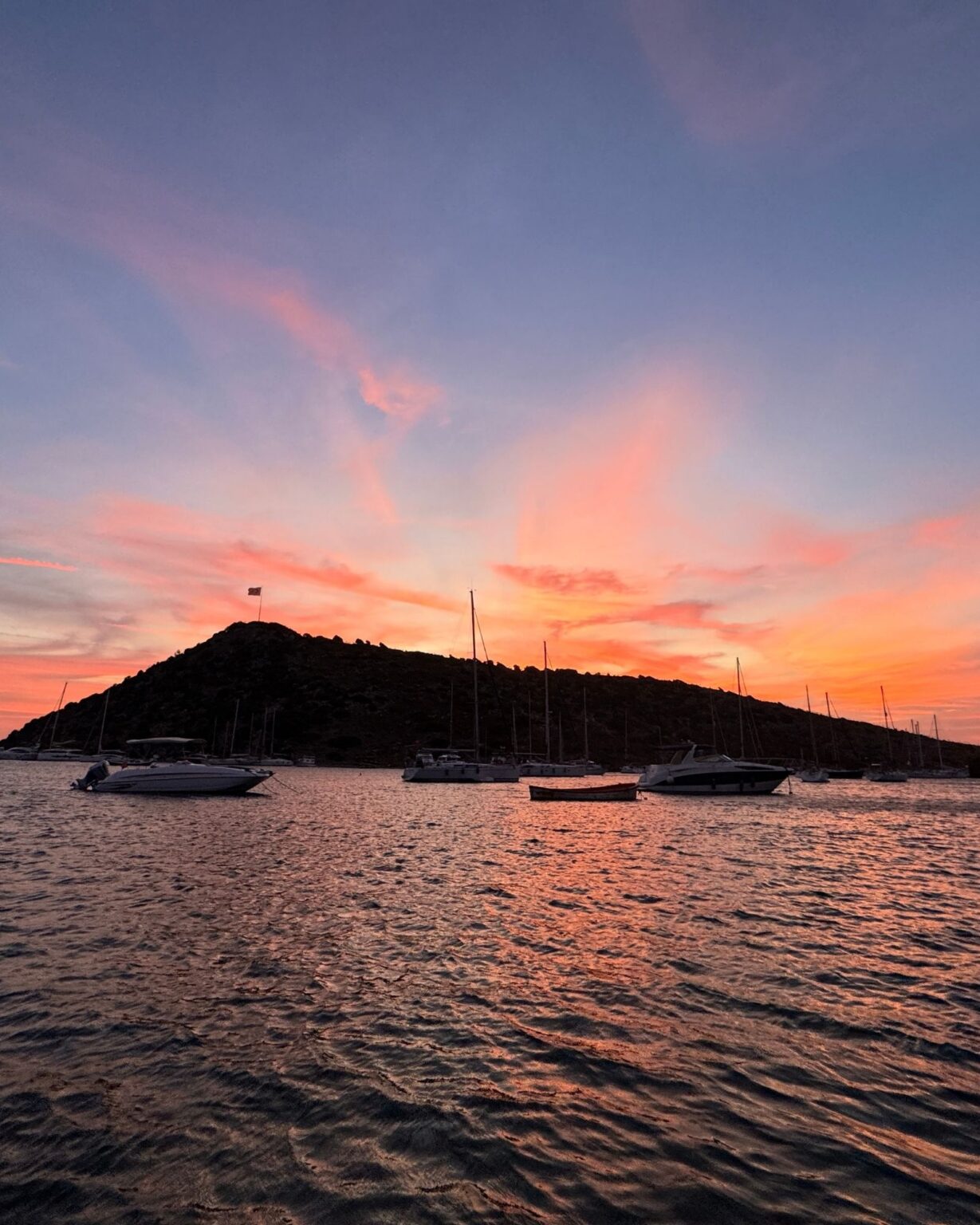 Kulinarische Highlights in Bodrum: Sonnenuntergang auf dem Meer mit Blick auf einen Berg und Boote.